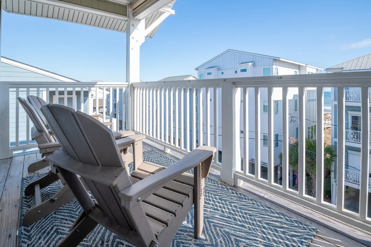 This exterior shot highlights a cozy outdoor seating area with Adirondack chairs and an outdoor rug, offering a calm space to enjoy the view of neighboring buildings. The scene evokes relaxation and leisure, with an inviting atmosphere for watching sunsets, sunrises, or stargazing.