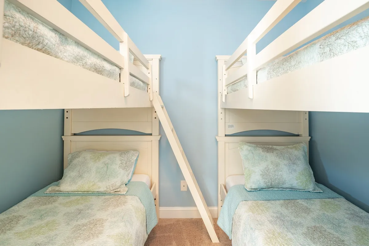 A playful and cozy bunk room with sturdy bunk beds and a ladder. The room is brightly lit and designed for comfort, making it perfect for kids or friends to rest or play. The cheerful decor invites fun sleepovers and shared memories.