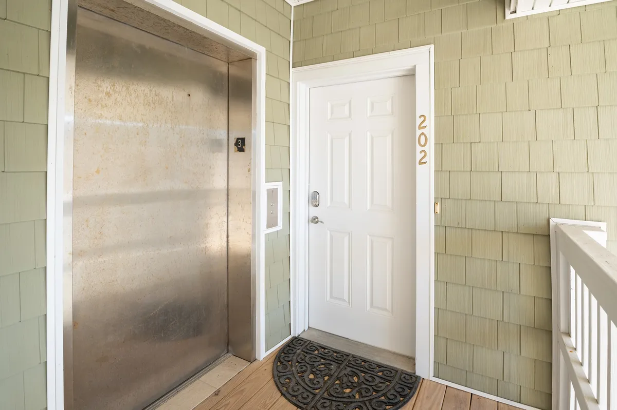 A view of the elevator in the entryway, adjacent to the front door with a welcoming doormat. The space is bright and functional, clearly showing the elevator amenity for easy access between floors.